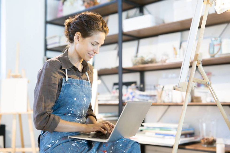 An artisan sitting in their studio with a laptop.